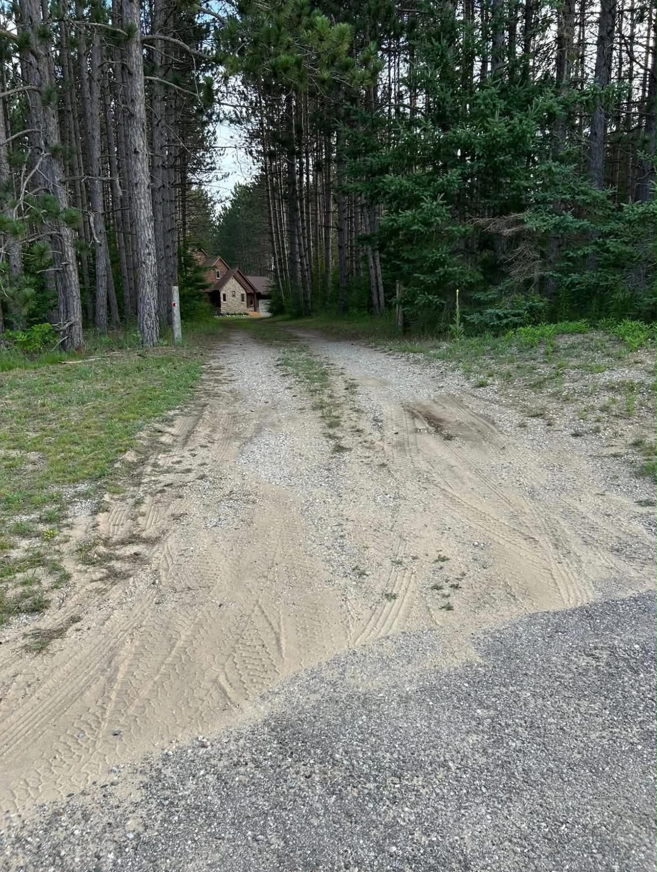 Gravel driveway before regrading, with potholes and standing water